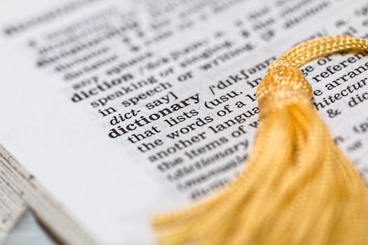 Close-up image of a dictionary page focused on the word 'dictionary' with a yellow tassel.