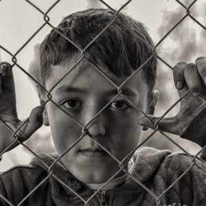 boy, fence, poverty, hungry, sad, sad boy, desperate, poor, child, captivity, chain link, chain link fence, grid, conceptidea, young boy, portrait, boy portrait, monochrome, black and white