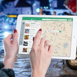 Hands using a digital map on a tablet in an urban setting at night, illustrating navigation and technology.