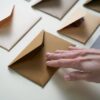 A hand gently touches brown envelopes spread on a white surface, illustrating organization.