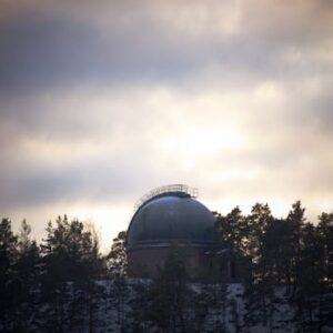 A captivating view of an astronomical observatory surrounded by trees under a moody sky.