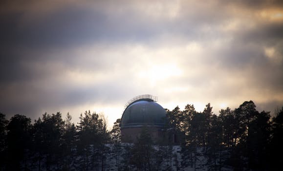 A captivating view of an astronomical observatory surrounded by trees under a moody sky.