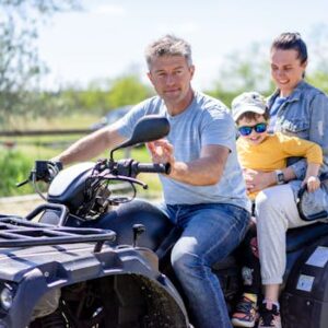 Father, mother, and child enjoying a fun ATV ride outdoors on a sunny day.