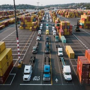 A bustling aerial shot of Seattle's shipping port with trucks lined up amongst colorful cargo containers.