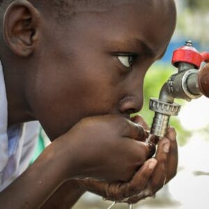 Close-up of a child drinking water from a faucet in Mwanza, Tanzania.