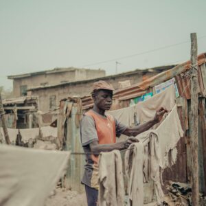 A man handling laundry outdoors in a rustic setting. Daily chores depicted in a natural, candid moment.