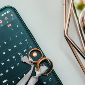 Elegant setup of wedding rings on a smartphone displaying a calendar date, symbolizing planning and celebration.