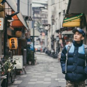 A man exploring a lively shopping street filled with signage and shops in Japan.