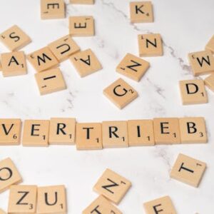 Scrabble tiles arranged to spell 'Vertrieb' on a marble surface, symbolizing sales.