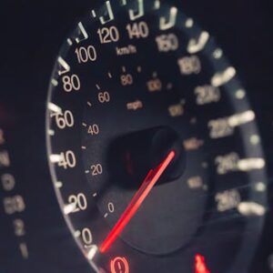 Detailed view of a car speedometer showing km/h and mph in low light settings.