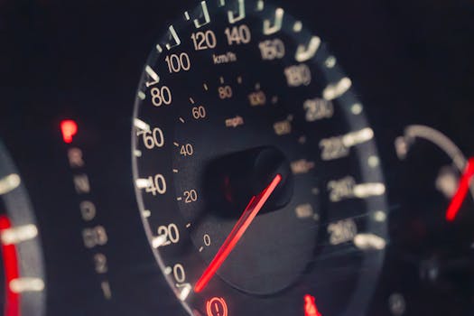 Detailed view of a car speedometer showing km/h and mph in low light settings.