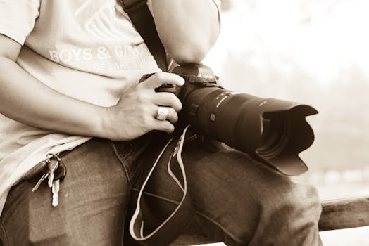 Close-up of a photographer sitting with DSLR camera outdoors, holding keys.