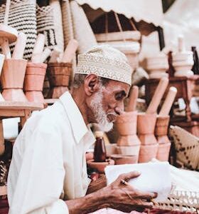 Senior man selling handmade wooden crafts at an outdoor market, showcasing traditional craftsmanship.