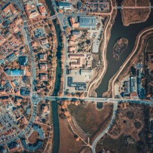 Aerial shot capturing the intricate city layout with roads, buildings, and a body of water.