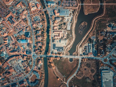 Aerial shot capturing the intricate city layout with roads, buildings, and a body of water.