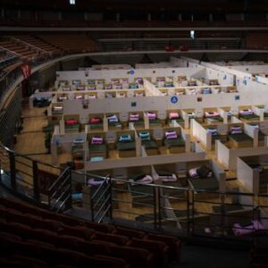 Interior view of a temporary healthcare facility inside a converted stadium with beds prepared for patients.