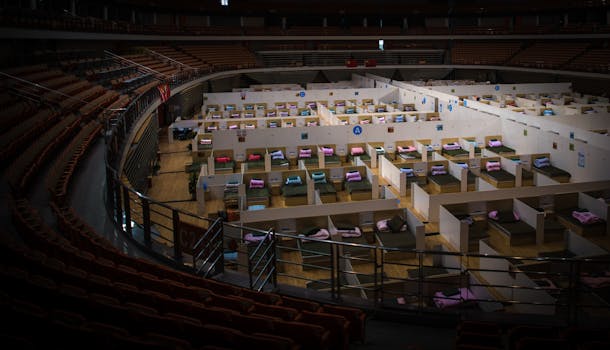 Interior view of a temporary healthcare facility inside a converted stadium with beds prepared for patients.