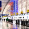 Wide view of Chicago airport terminal showcasing architecture and check-in counters. Flags and signages add vibrant detail.