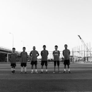 Black and white photo of a youth soccer team lined up on a field beneath an overpass.
