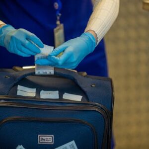 Close-up of airport security process with gloved hands inspecting luggage tags.