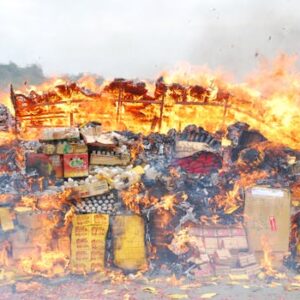 A large bonfire outdoors with assorted boxes and items engulfed in flames.