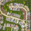 Vibrant aerial view of a residential neighborhood surrounded by dense green forest.