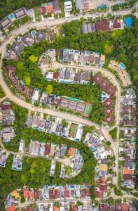 Vibrant aerial view of a residential neighborhood surrounded by dense green forest.