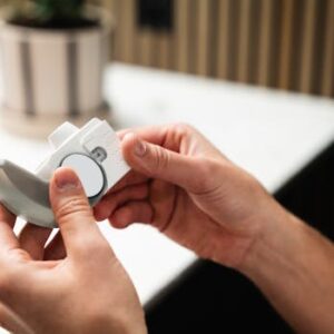 Close-up of hands holding an asthma inhaler, indoors in a modern setting.