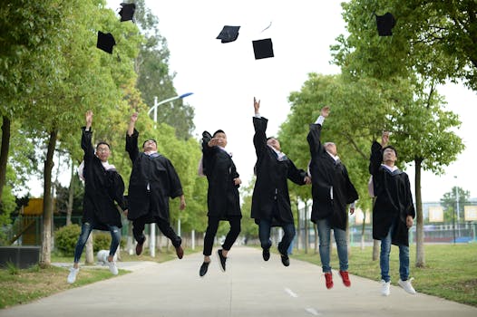 A joyful group of graduates throwing caps in the air during a graduation ceremony in a park setting.