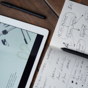 Digital and handwritten brainstorming tools on a wooden desk, ideal for business and study contexts.