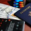 A close-up image of a U.S. passport, dollar bills, and a smartphone.