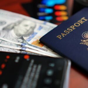A close-up image of a U.S. passport, dollar bills, and a smartphone.