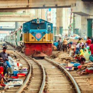 Vibrant image of a train passing through a lively outdoor market surrounded by people.