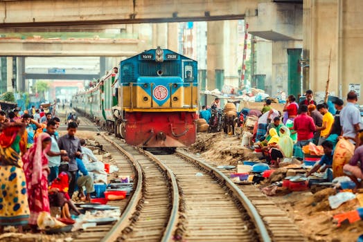 Vibrant image of a train passing through a lively outdoor market surrounded by people.