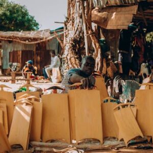 Skilled artisans handcraft traditional Nigerian items in a vibrant outdoor market setting, showcasing cultural craftsmanship.