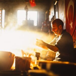 A potter in Türkiye skillfully crafts pottery in warm sunlight, symbolizing artisanal heritage and creativity.