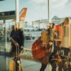 Passengers moving through an airport gate area with visible airplanes outside.