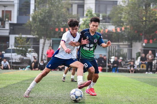 Two soccer players in action during a match on a lush green turf field in Hà Nội.