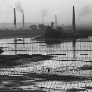 Black and white view of industrial smokestacks in Keraniganj, Bangladesh, reflecting in the river.