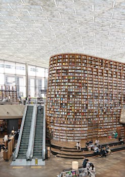 Interior view of a modern library in Seoul with a vast bookshelf and escalators under a glass ceiling.