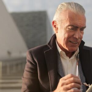 Senior businessman with tablet outdoors, adjusting eyeglasses, and reviewing business data.