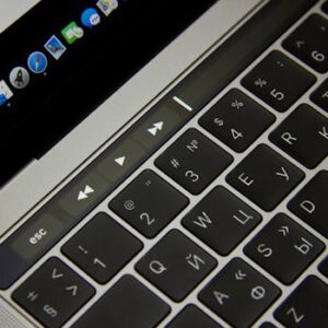 Close-up of a laptop keyboard showcasing Russian letters and a touch bar in a modern setting.