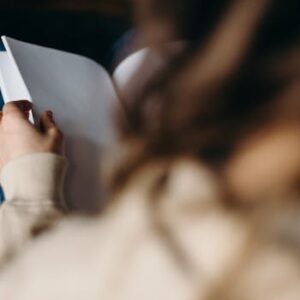 Close-up of an adult reading a blank notebook indoors, focused on the pages.
