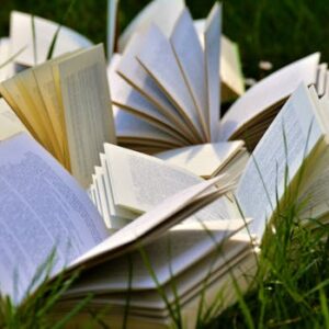 An artistic arrangement of open books in a grassy field, emphasizing a love for outdoor reading.