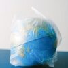 A globe encased in a plastic bag symbolizing environmental issues, recycling, and pollution.