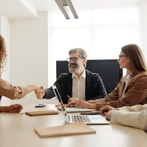 Colleagues in an office celebrating a successful negotiation with a handshake.