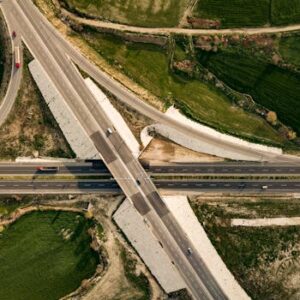 Drone shot of expressway intersection surrounded by vibrant green fields.