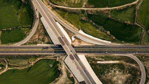 Drone shot of expressway intersection surrounded by vibrant green fields.