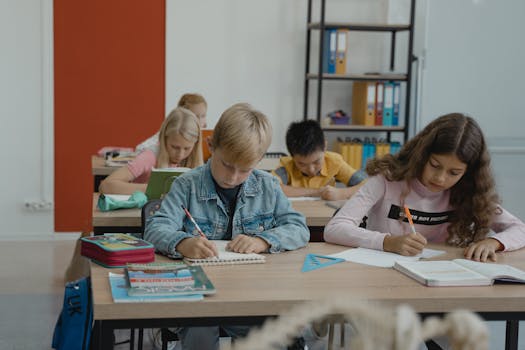 A group of children studiously engaged in writing and learning in a vibrant classroom setting.