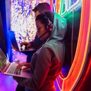 Team of cyber security experts working on laptops in a vibrant neon-lit room.